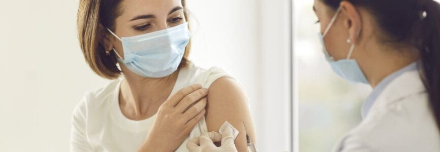 Young patient in a medical face mask getting an antiviral vaccine at the hospital