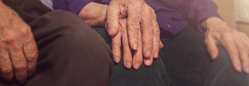 Elderly couple hands. Husband holding wife's hand for support. Nursing home. Age-related diseases. Love to the death.