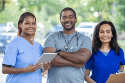 three smiling nurses outside under trees