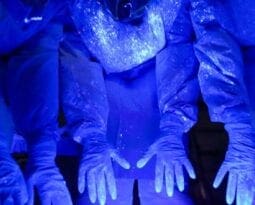 blue hands and body glowing under blacklight, showing the germs on their hands and bodies