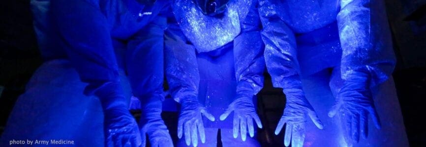 blue hands and body glowing under blacklight, showing the germs on their hands and bodies