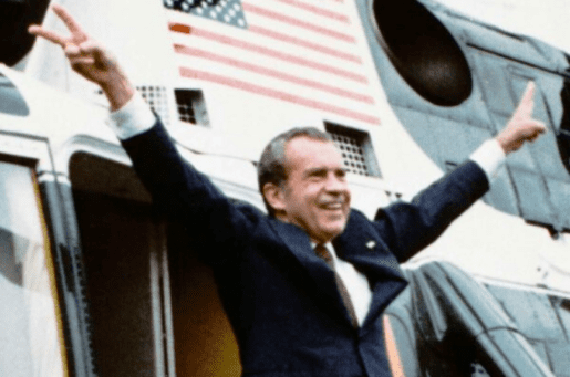 photo of former president nixon with arms outspread and fingers in v sign