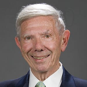 aging white man against a grey background, smiling