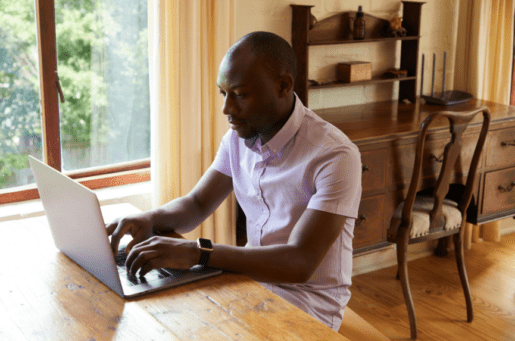 african american man in pink shirt on computer