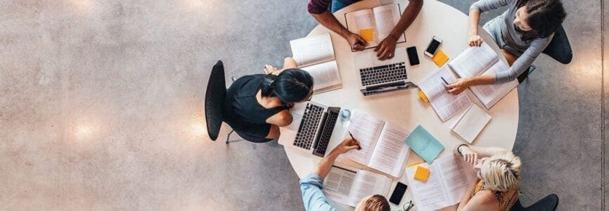 Top view of group of students sitting together at table. University students doing group study.