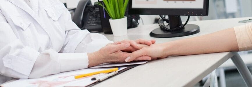 doctor holding patient's hand, plant in background, possibly discussing abortion