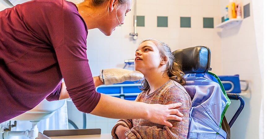 Disabled child in a wheelchair being cared for by a special needs nurse / Working with disability