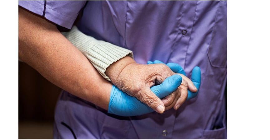 Doctor holding elderly patient's hands with care.