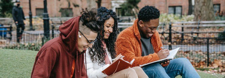 three young people of color laughing on lawn