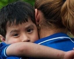 small boy wrapped around a woman's chest and shoulders