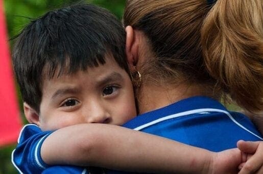 small boy wrapped around a woman's chest and shoulders