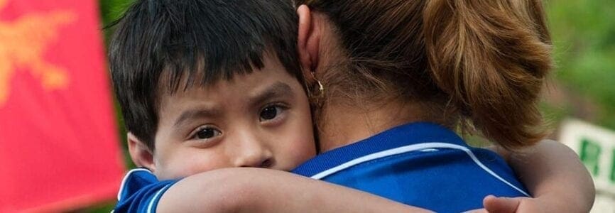 small boy wrapped around a woman's chest and shoulders