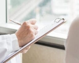 man holding a chipboard and taking notes on it