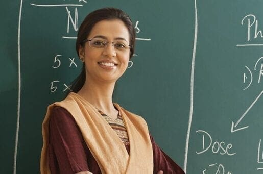 smiling woman standing in front of a chalkboard