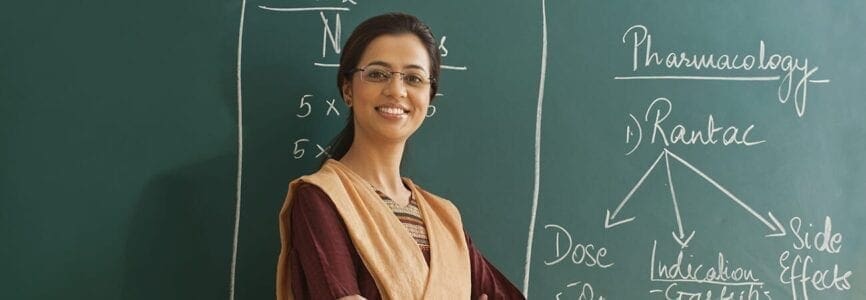 smiling woman standing in front of a chalkboard