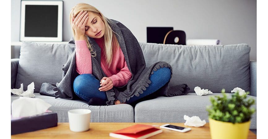 Sick woman with headache sitting under the blanket