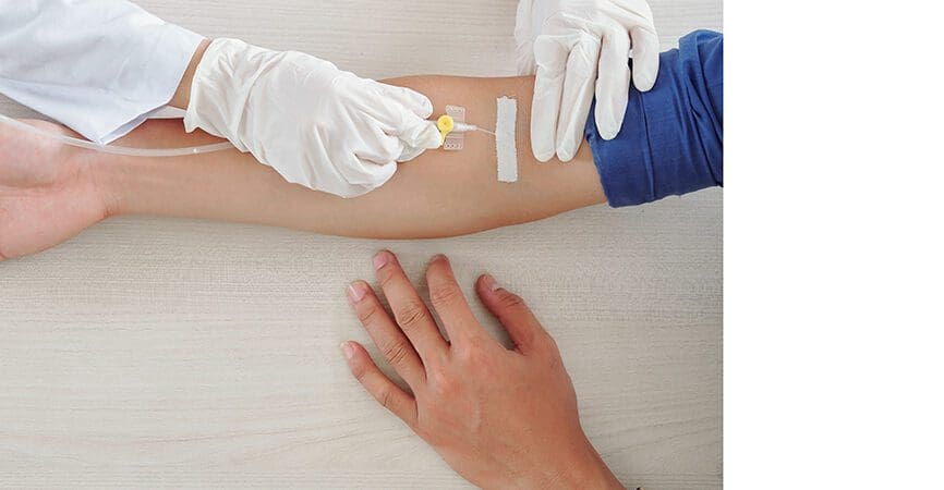 Male patient getting infusion therapy in hospital, medical nurse inserting venous catheter in arm vein