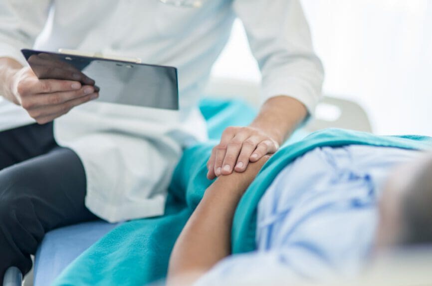 doctor at bedside holding patient's hand