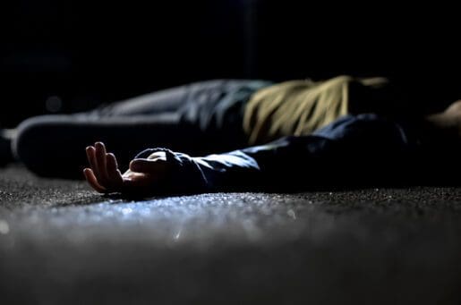 injured Black woman lying in the street at night