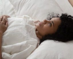 young black woman lying on her back, looking concerned