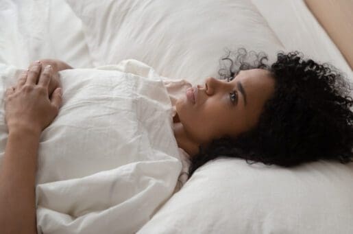 young black woman lying on her back, looking concerned