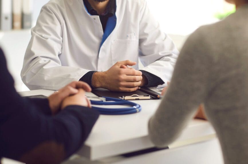 couple sitting at desk with doctor