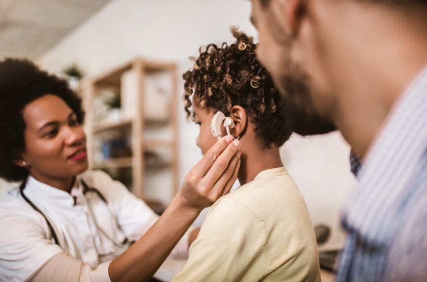 African American nurse checks African American girl with hearing aid