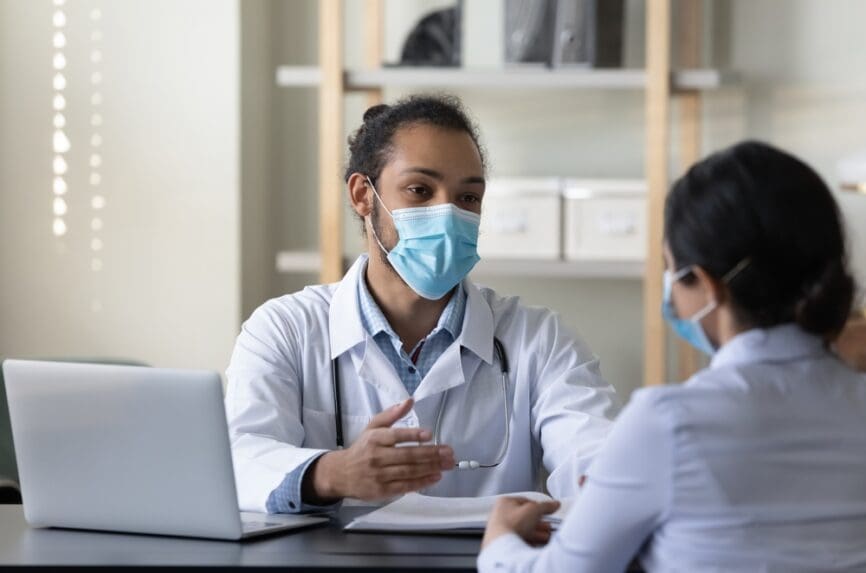 young black doctor talking with a female patient at desk