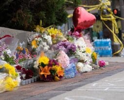 bouquets of colorful flowers layed on sidewalk along with balloons