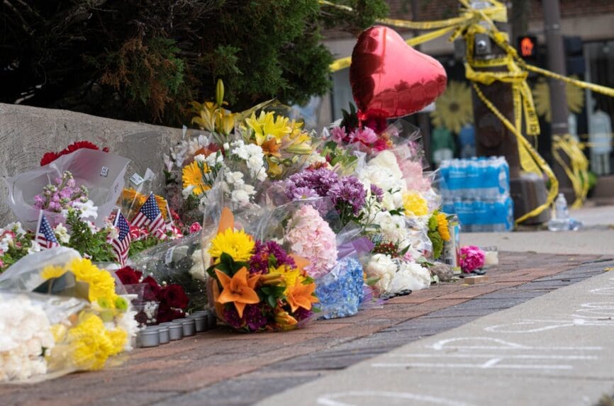 bouquets of colorful flowers layed on sidewalk along with balloons