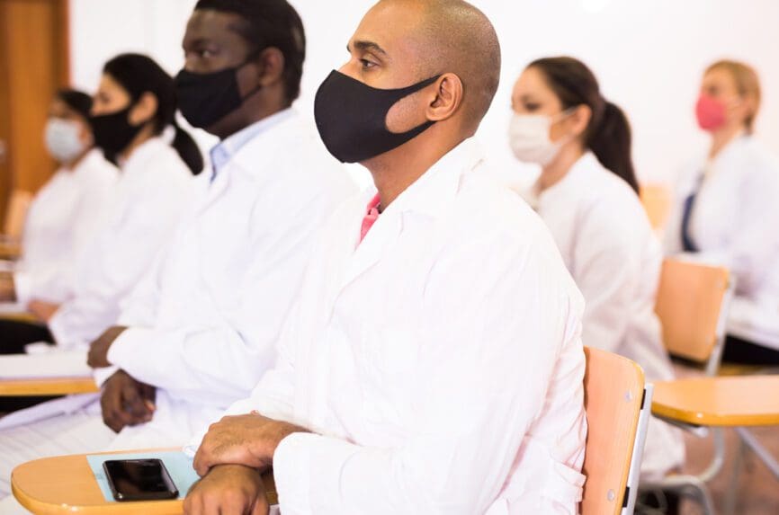 people standing in white clothes with black masks at desks