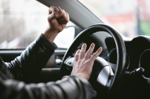 car driver's hands honking horn and forming fist