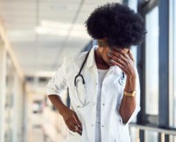 Black female doctor with her head in her hand