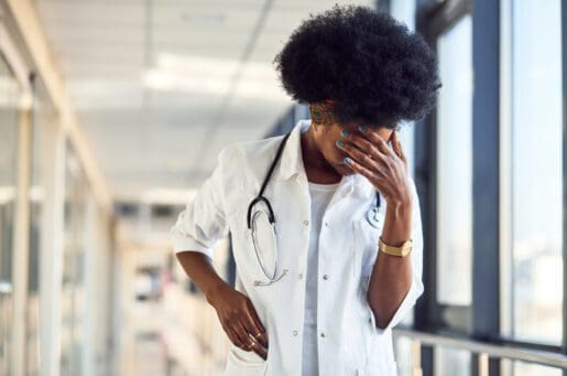 Black female doctor with her head in her hand