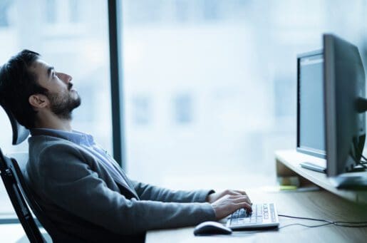 stressed young man sitting at desk with computer