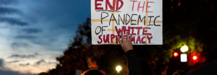 man of color holding a white sign stating 