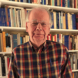 older white man surrounded by books